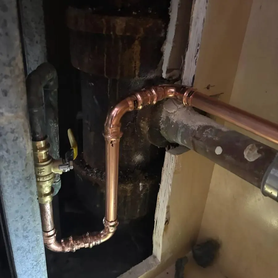 New copper supply pipe soldered in beside an older galvanized line at a water heater riser